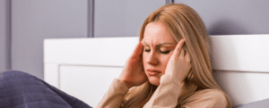 Lady sitting up in bed with a tension headache